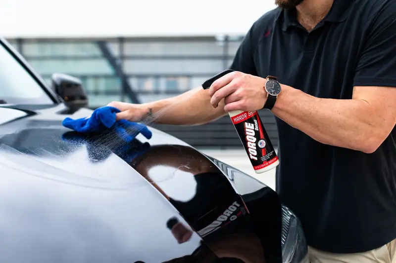 Spray and a microfiber towel on a black hood